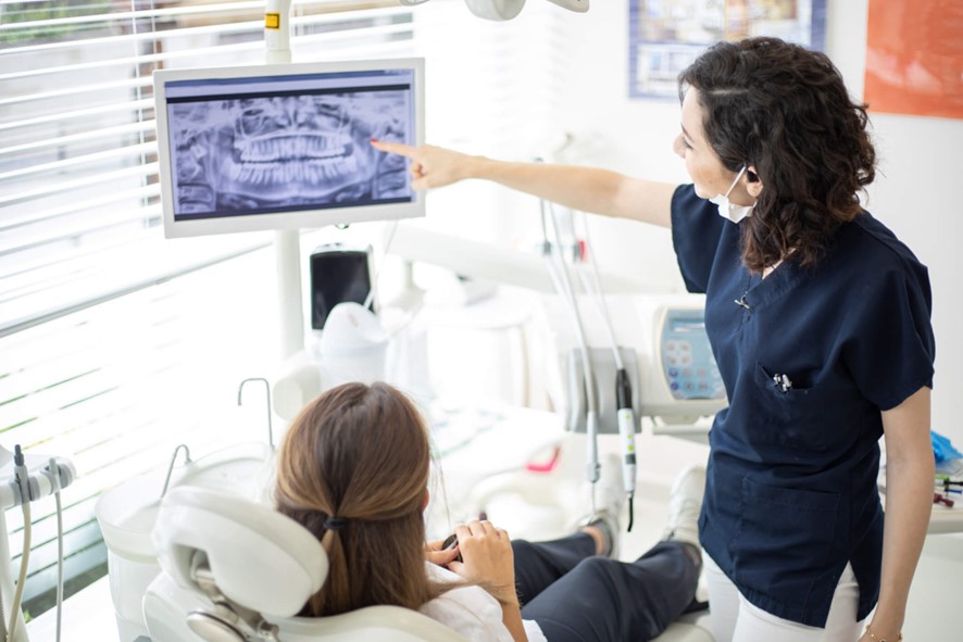 A dentist showing a patient an X-ray on a screen